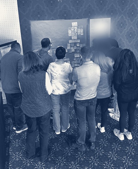 A team gathered at a wall of sticky notes during an Unmute session